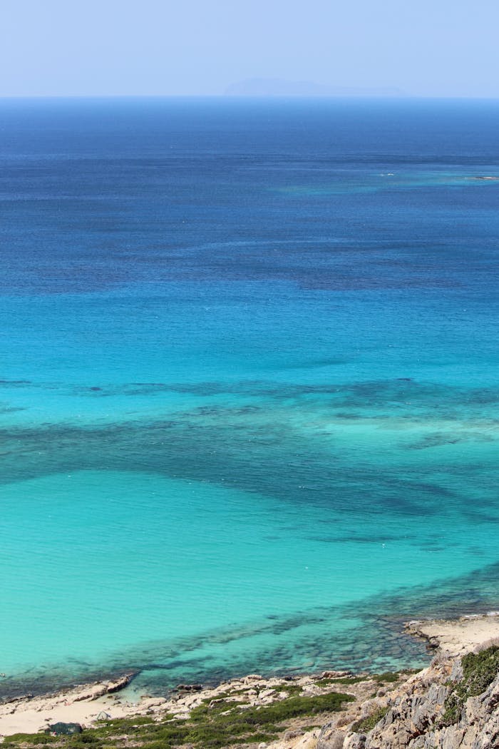 gallery-06 From above of azure calm ocean near stony shore against blue sky line on horizon in summer day in tropical resort